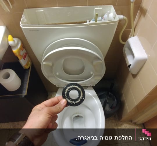 יד מחזיקה אטם גומי מול אסלה פתוחה